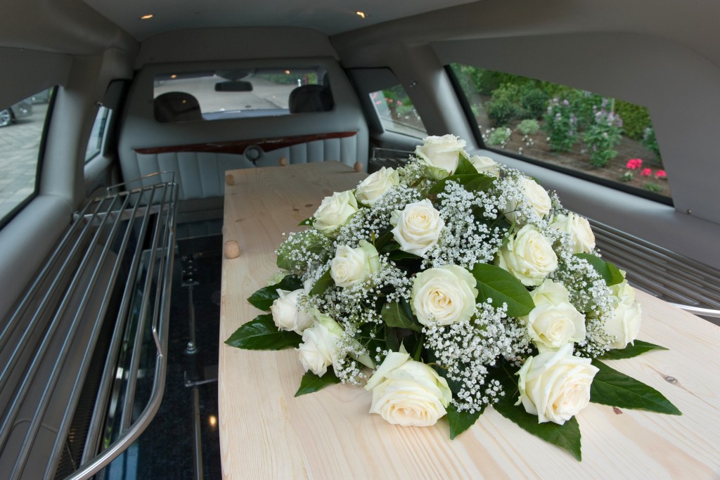 A coffin in a mourning car with a flower arrangement